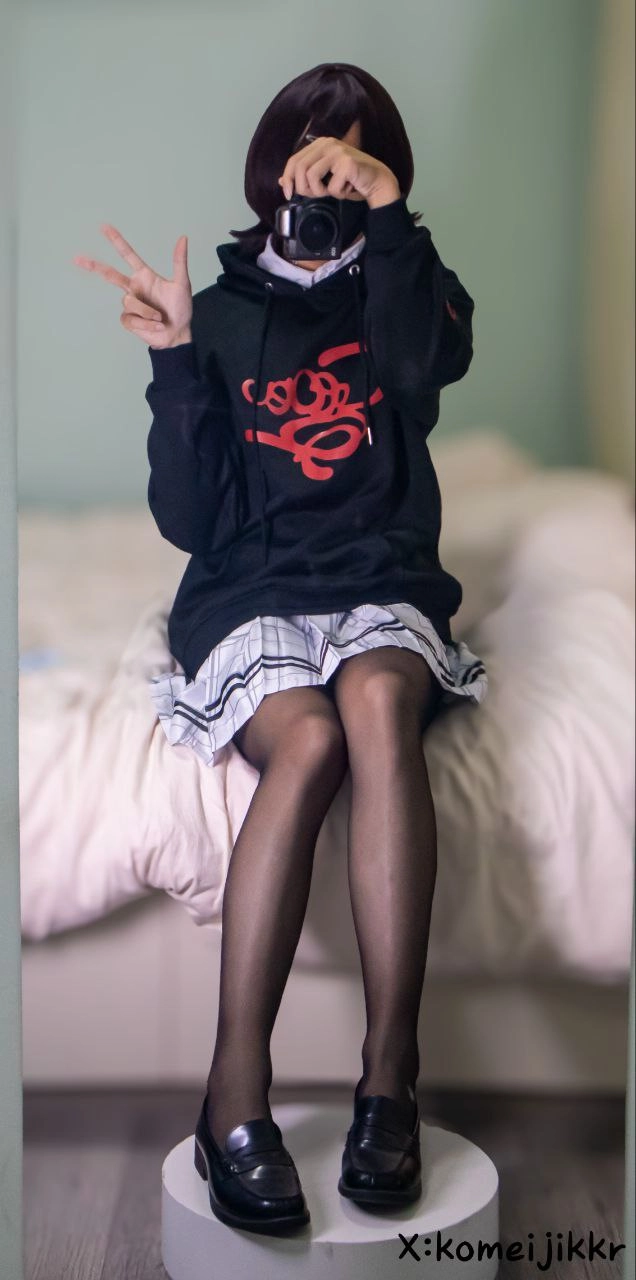 穿着红色标志的黑色毛衣的女孩坐在床上。