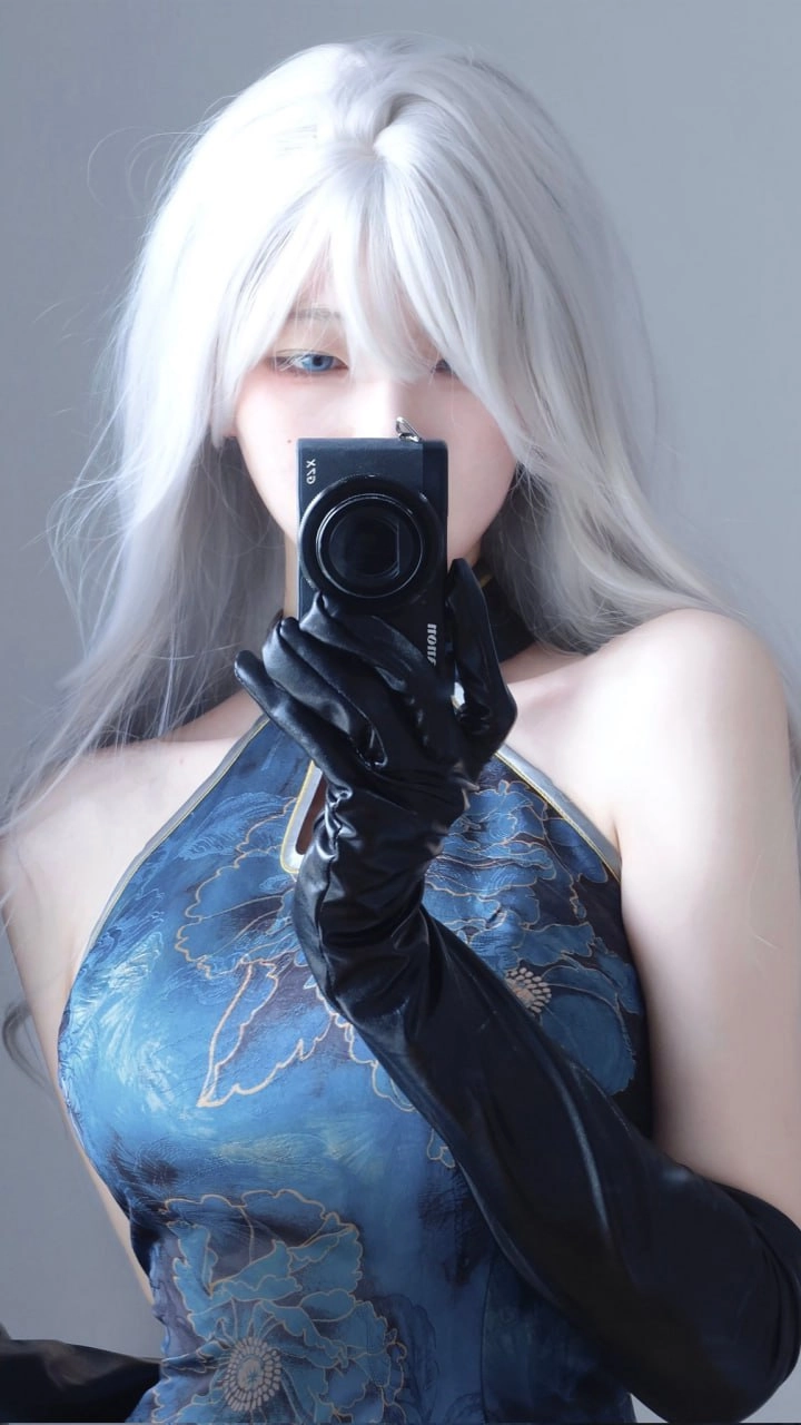 穿着蓝色衣服的女人用相机拍照自己。