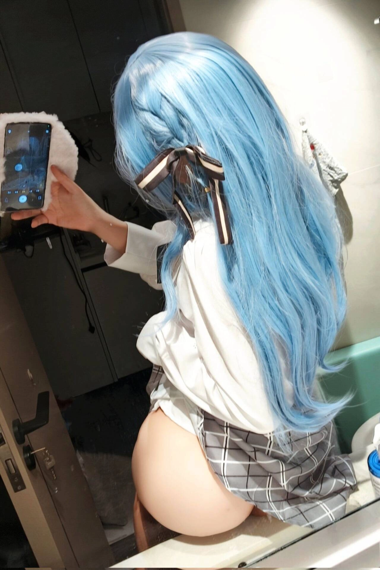 蓝头发和黑弓的女人在镜子里拍个自拍。