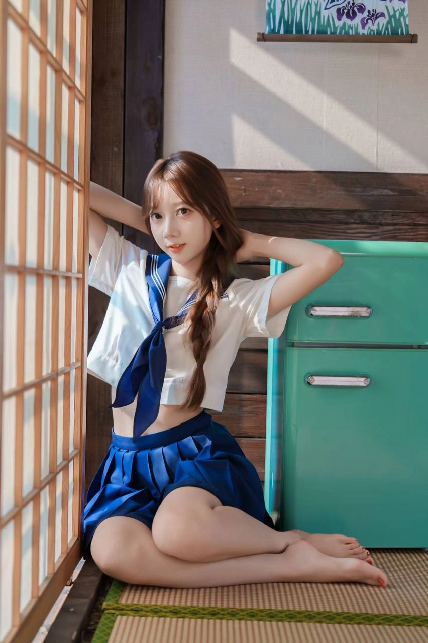 一位穿着蓝色和白色的水手制服的年轻女子坐在地板上,读了一本书。