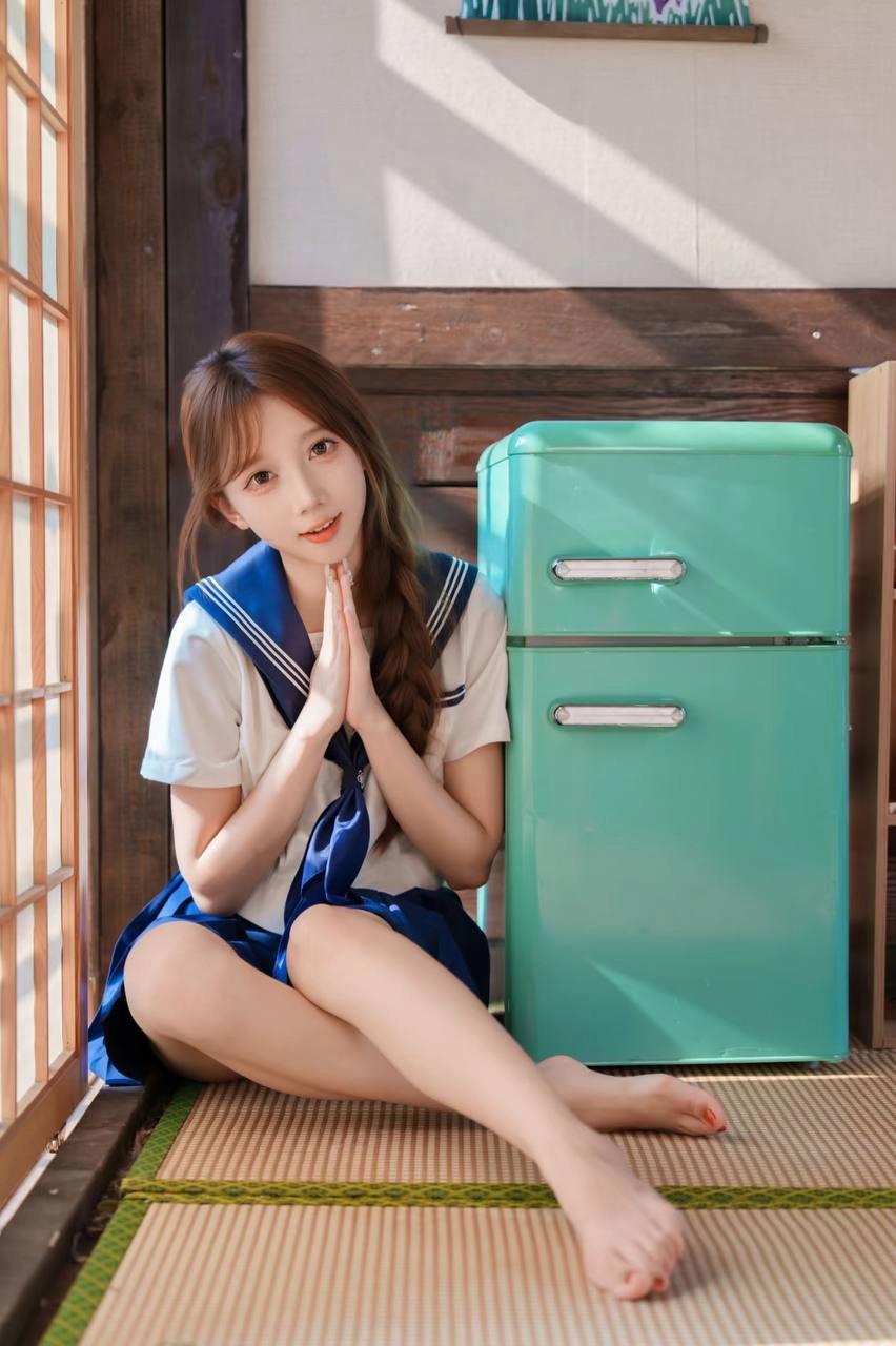 一位穿着蓝色和白色的水手制服的年轻女子坐在地板上,读了一本书。