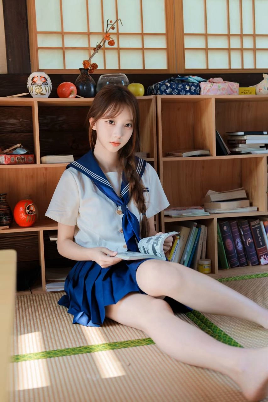 一位穿着蓝色和白色的水手制服的年轻女子坐在地板上,读了一本书。