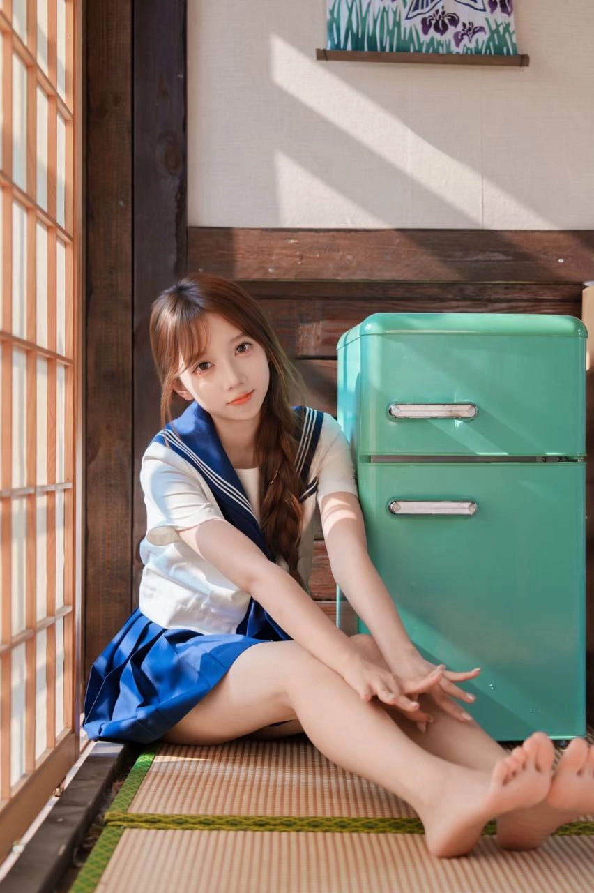 一位穿着蓝色和白色的水手制服的年轻女子坐在地板上,读了一本书。