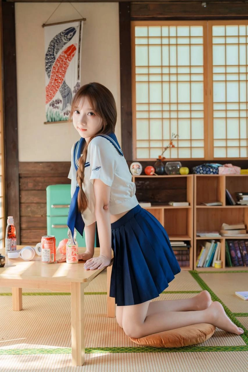 一位穿着蓝色和白色的水手制服的年轻女子坐在地板上,读了一本书。