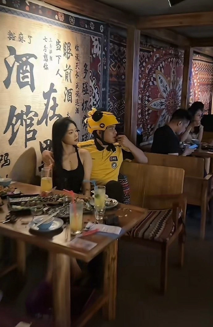 穿着黄头盔的男人坐在一家餐厅的女人旁边。