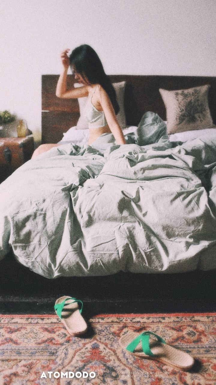 一位穿着白色坦克的女人躺在床上。