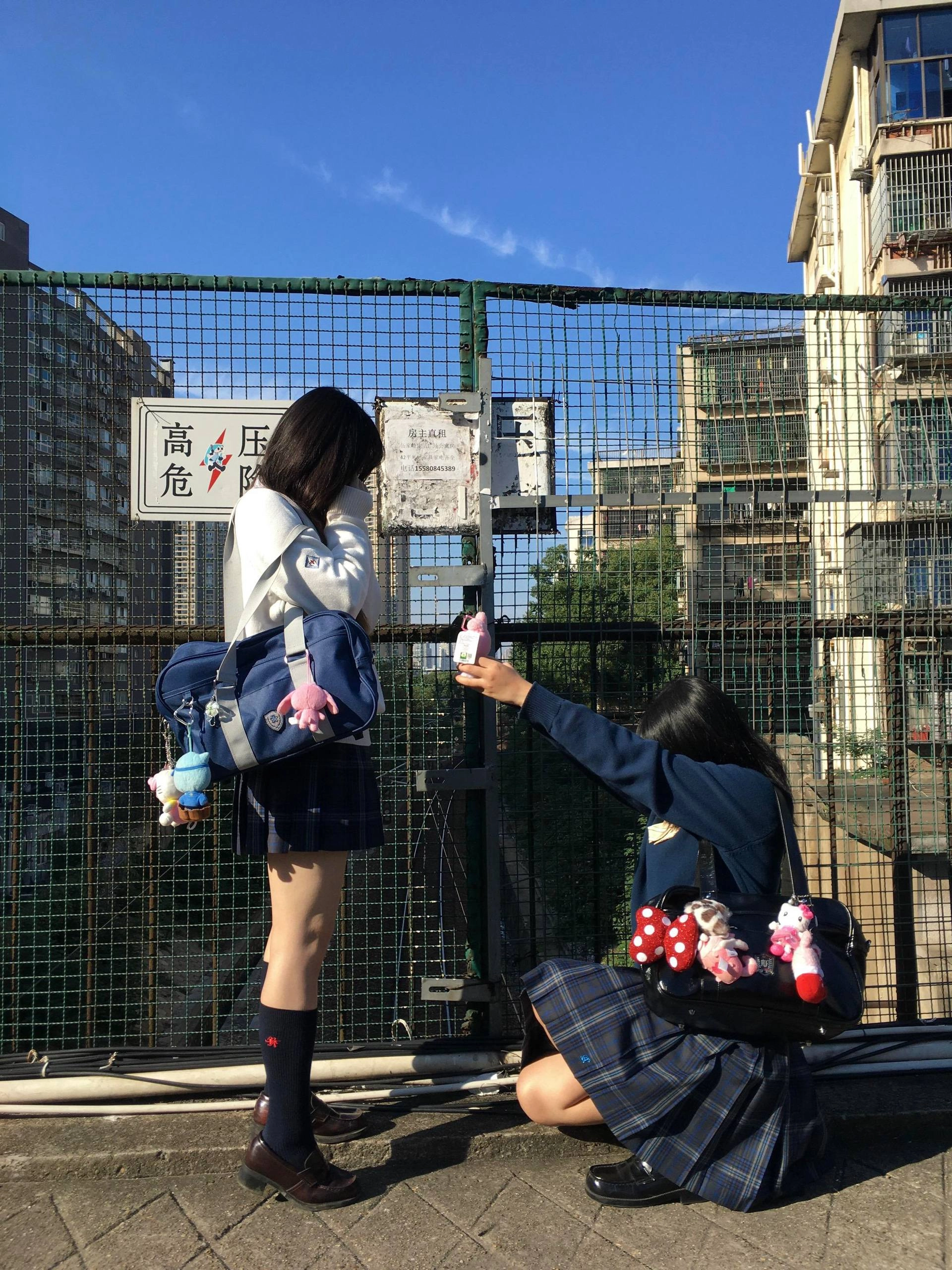 两个女孩在桥上,拍摄对方的照片。