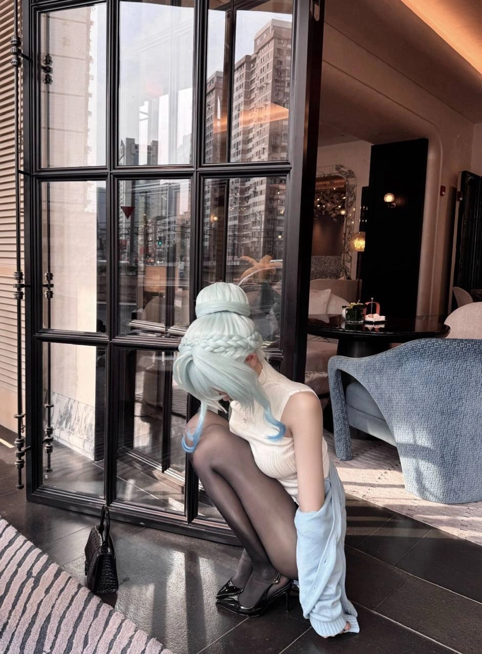 蓝头发和白衬衫的女人坐在地板上。