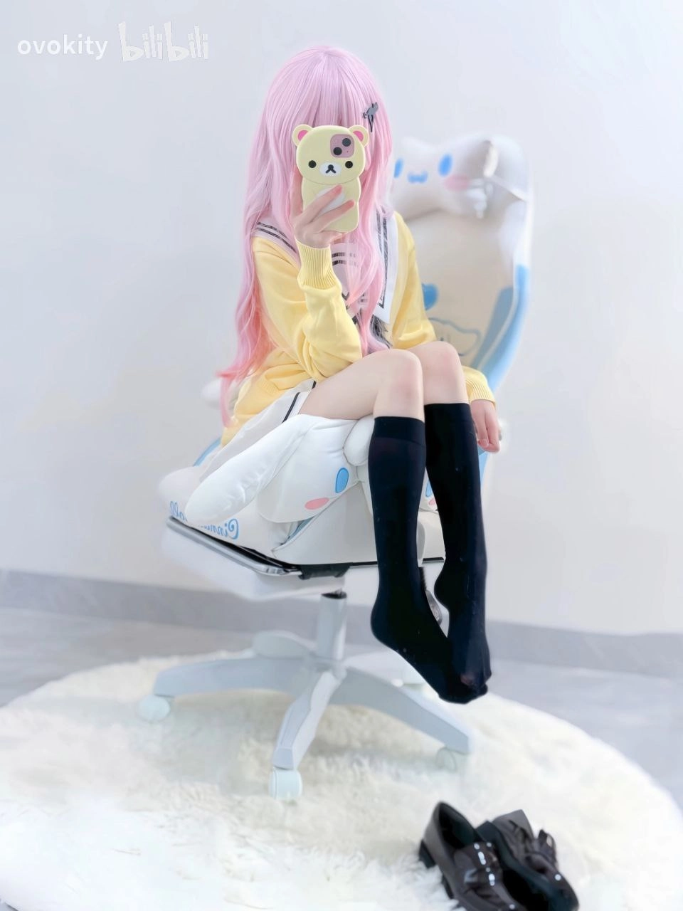 一位穿着黄色衬衫和黑色袜子的女人坐在椅子上,拍照她的手机。