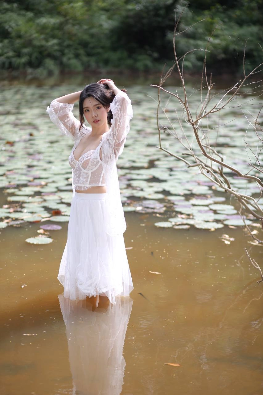 穿着白色衣服的女人站在一个池塘里。