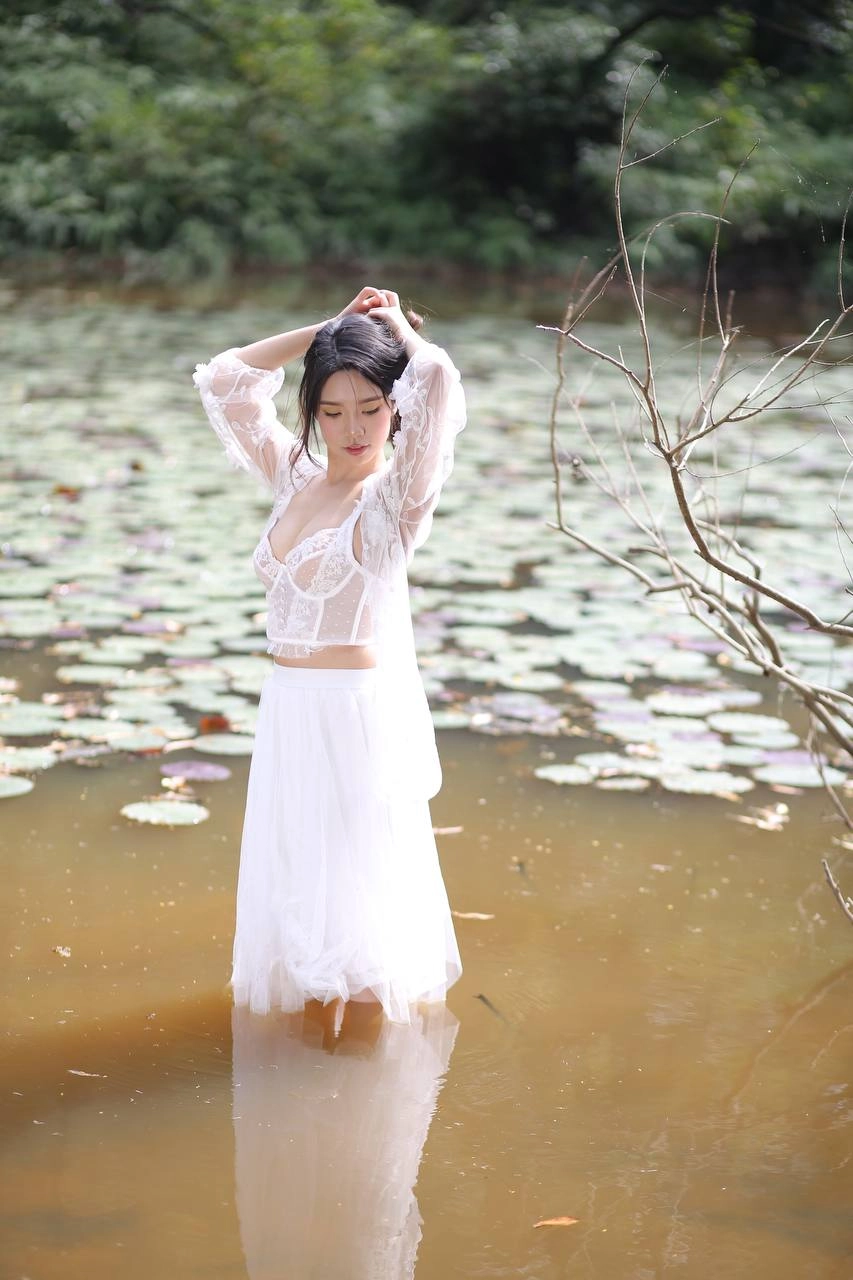 穿着白色衣服的女人站在一个池塘里。