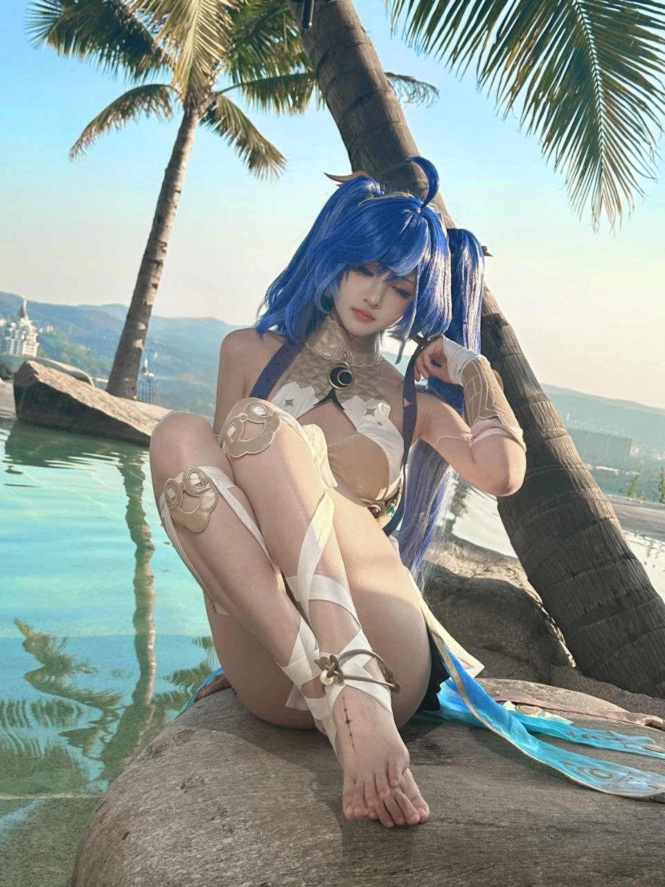 穿着蓝色裙子的女人坐在一块岩石上。