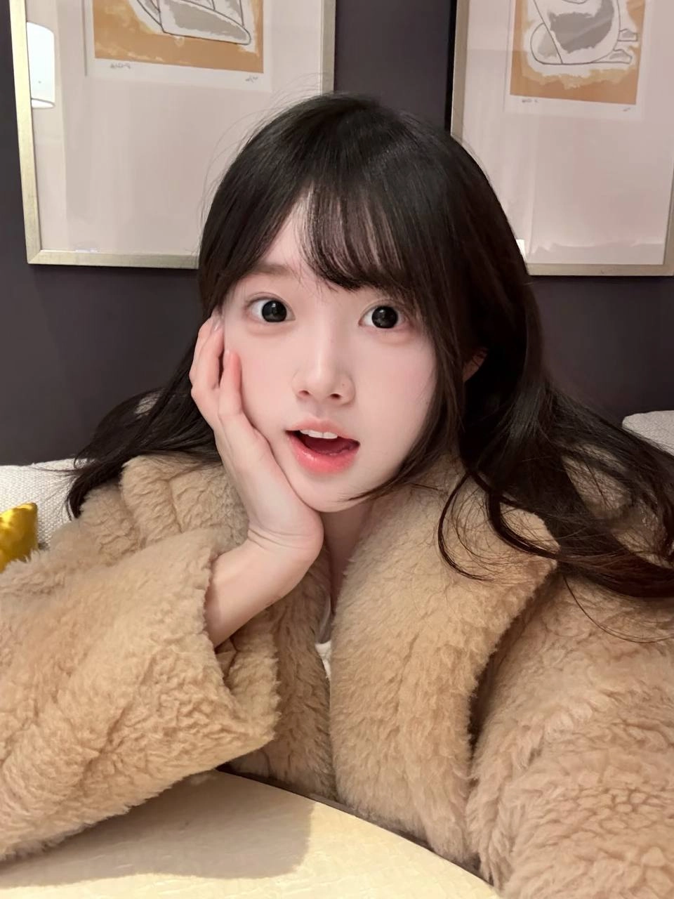 戴着马尾巴和棕色外套的女孩微笑着。