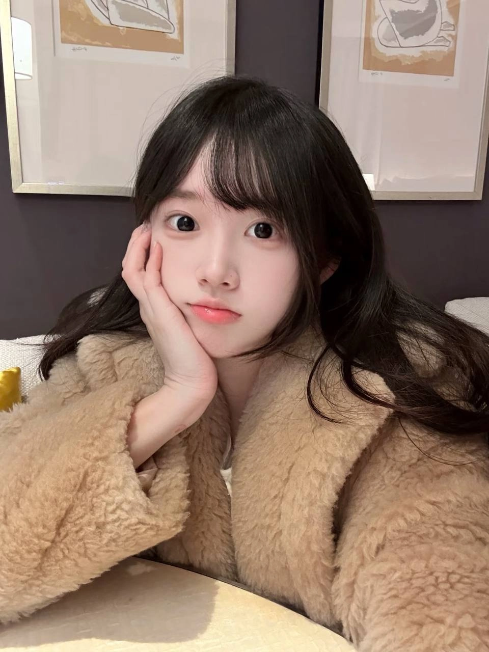 戴着马尾巴和棕色外套的女孩微笑着。