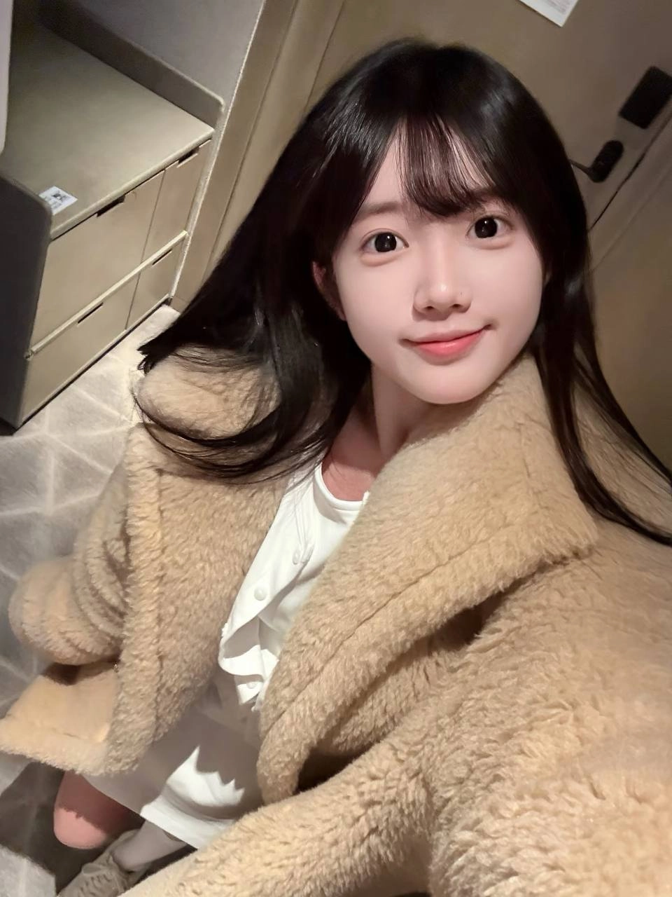 戴着马尾巴和棕色外套的女孩微笑着。