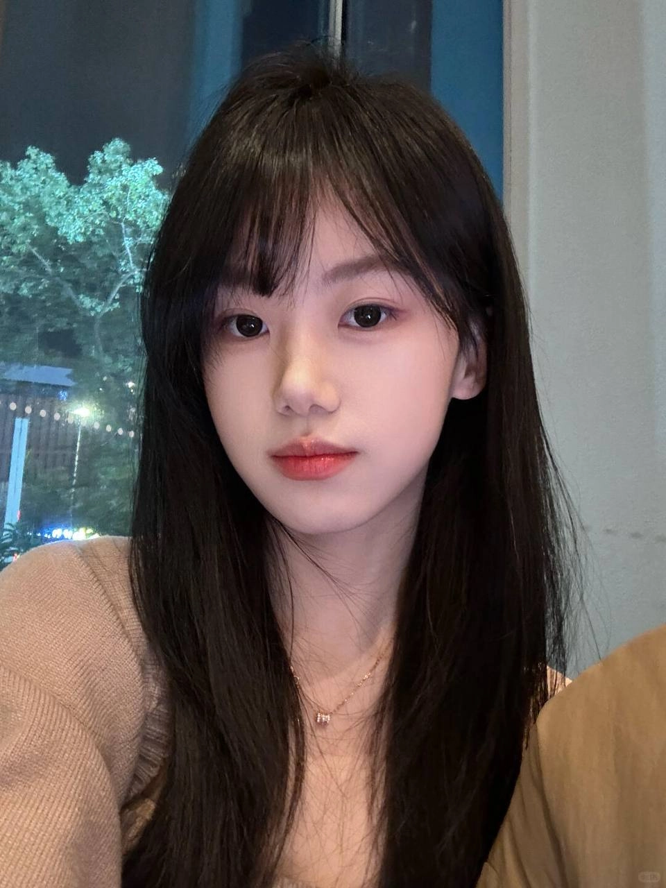 长黑头发和粉红色的唇膏的女人对相机微笑。