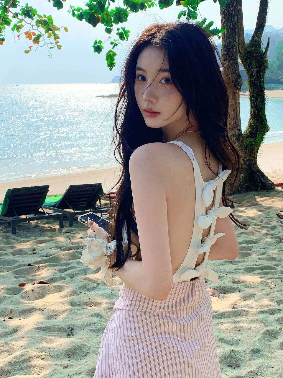 一位穿着白色浴衣的女人拿着手机。