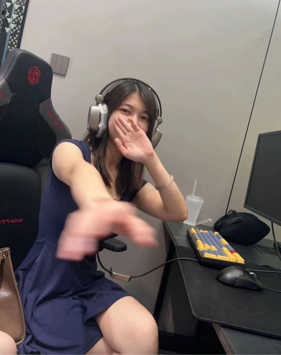 一位戴着耳机和蓝色裙子的女人坐在一张桌子上。