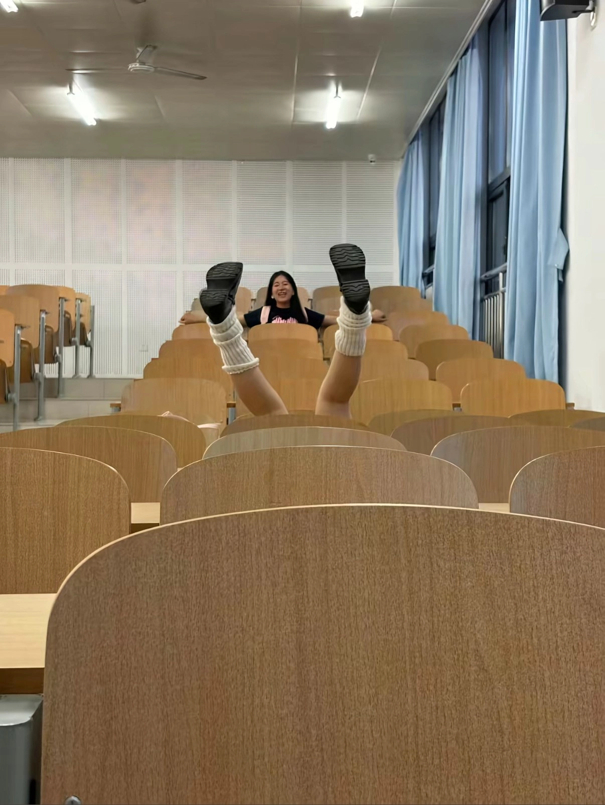 女人坐在教室里,她的腿在椅子上。