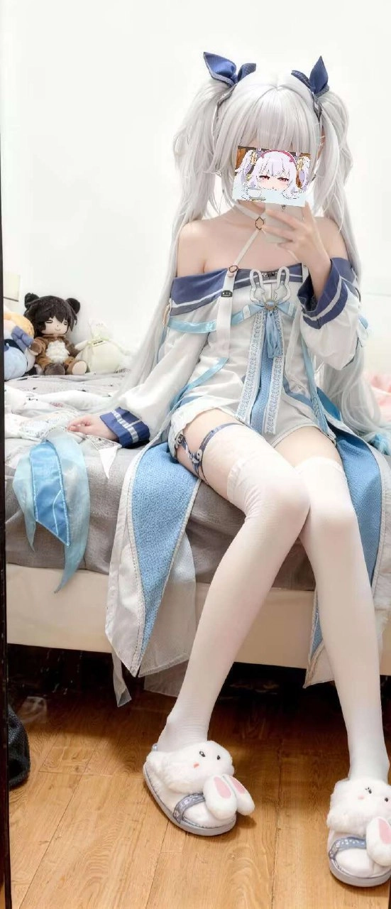 穿着蓝色口音的白色裙子的女人坐在床上。