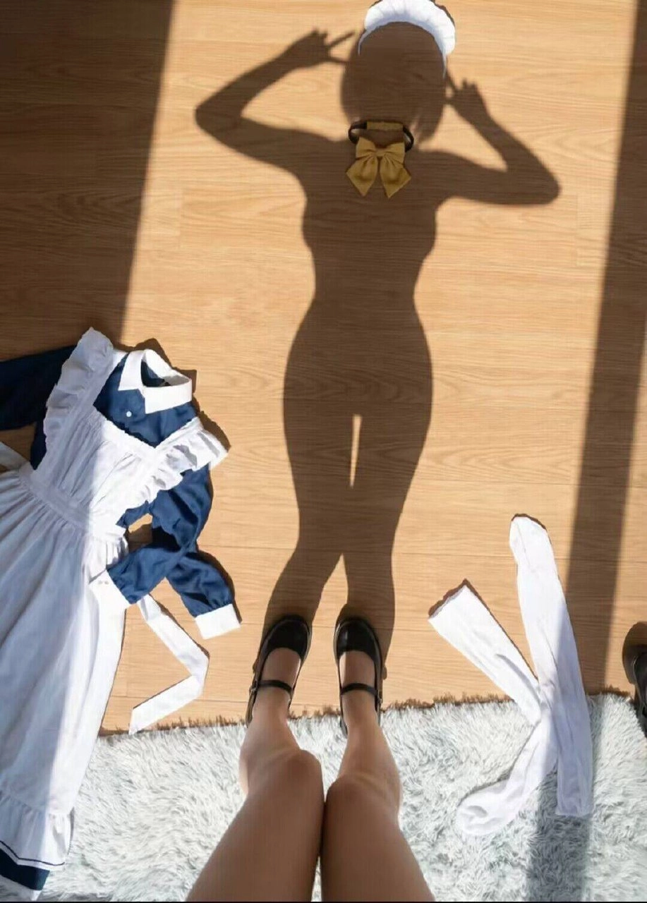 一位穿着蓝色裙子和黑色鞋子的女人站在木地板上。